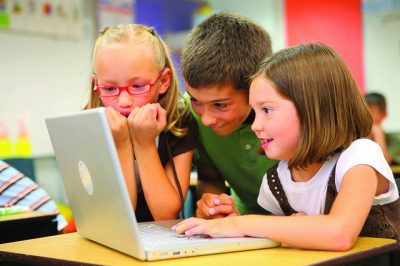 An image of children enjoying themselves on a laptop