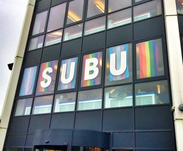 A photograph of the BU student union building with rainbow pride flags hung up in the windows
