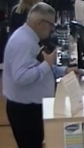 A CCTV image of a middle-aged man using a credit card in a shop