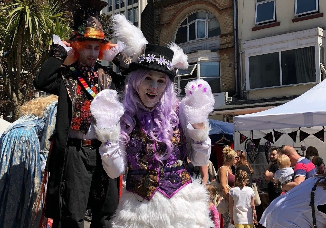 Street performers on stilts in Alice in Wonderland fancy dress