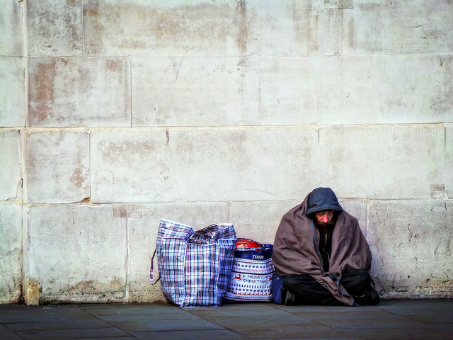 Homeless man sat by wall