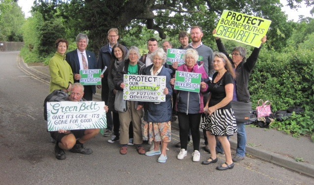 Campaign group standing with placards in front of a field