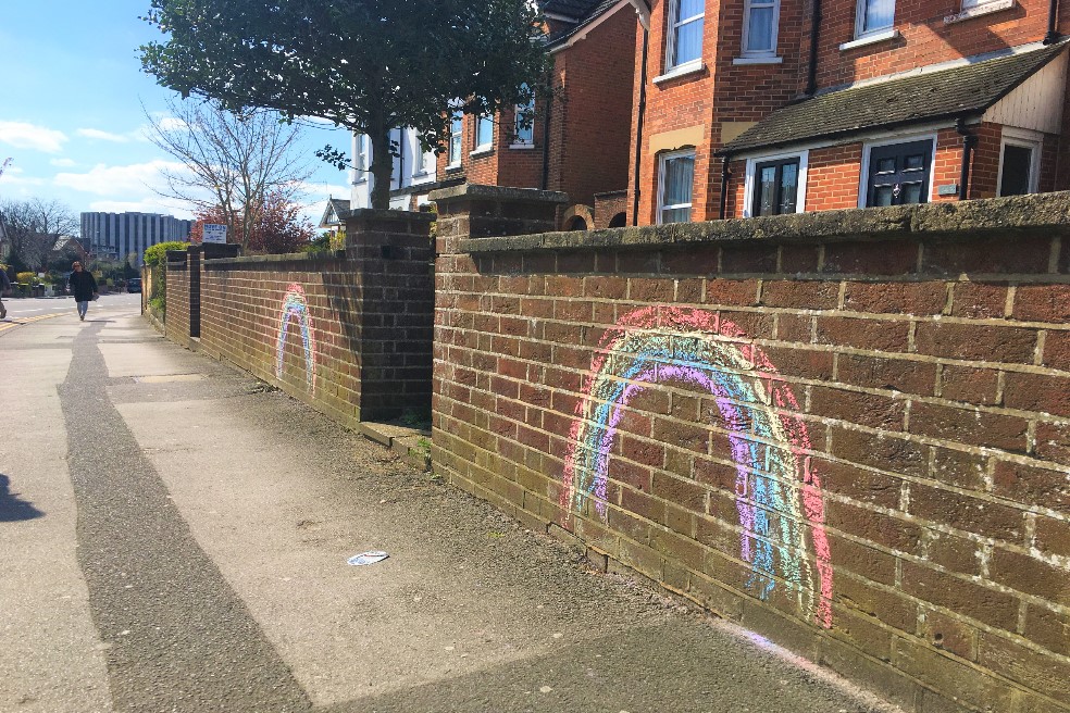 An image of rainbows drawn in chalk on a wall outside a home