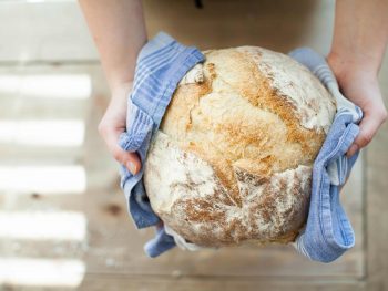 A woman holds a fresh loaf of bread
