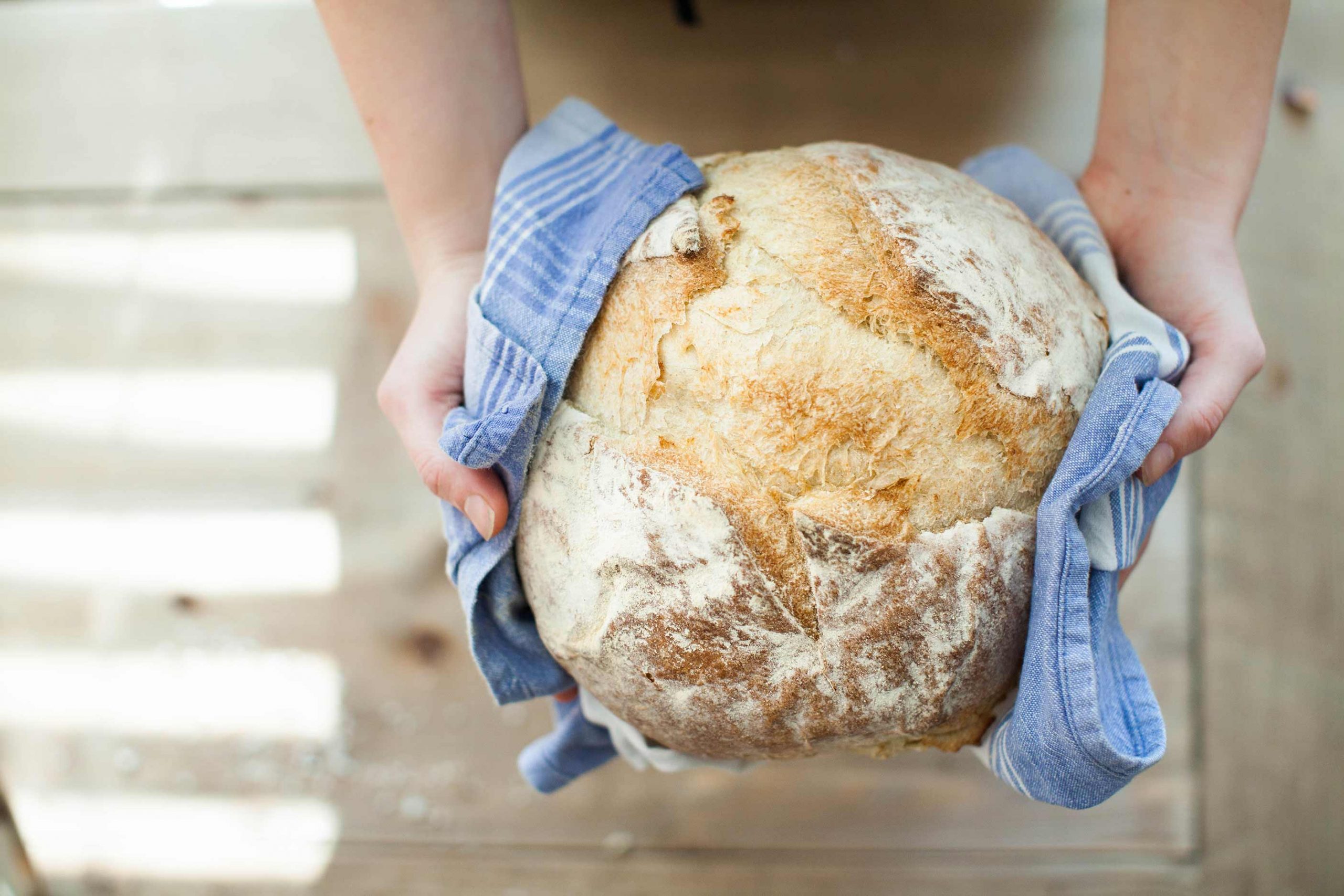 A woman holds a fresh loaf of bread