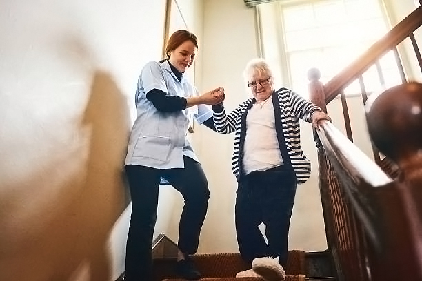 Photo shows young female carer helping an elderly woman in a care home during coronavirus pandemic