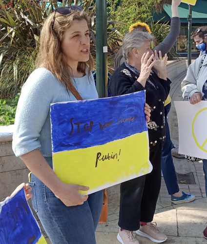 An Ukrainian woman stands holding a placard with a political message on it