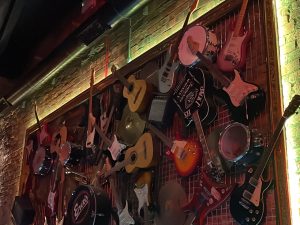 Photo of lots of different types and brands of guitars hung on the wall.