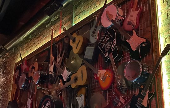 Photo of lots of different types and brands of guitars hung on the wall.