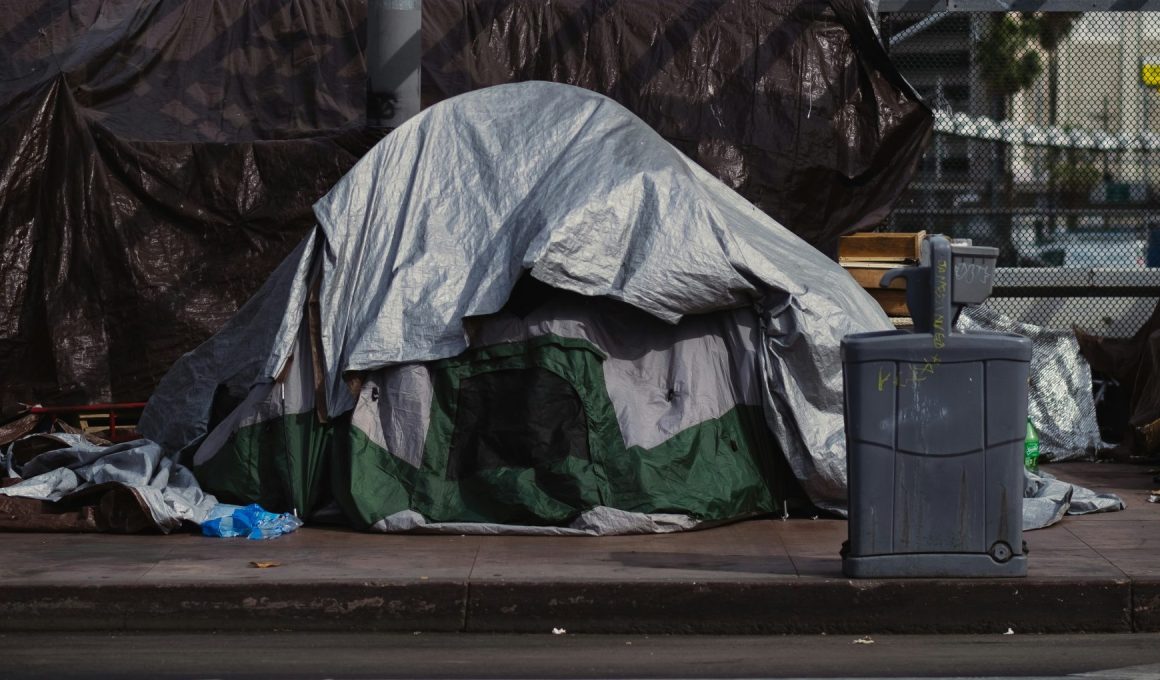 A tent outside in the middle of piles of rubbish.