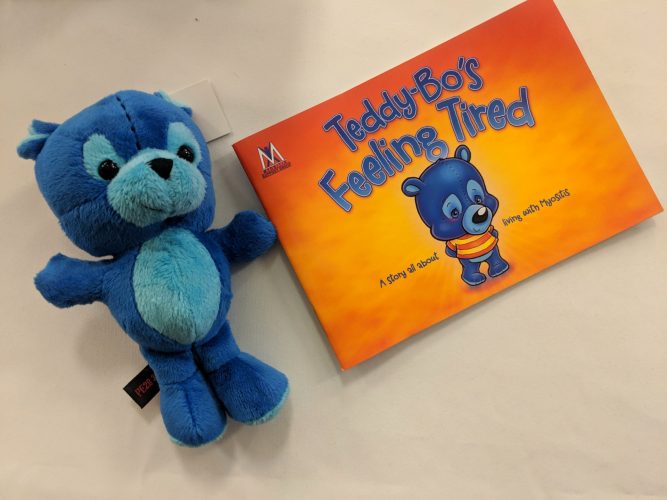 Photo of Myositis charity mascot 'Teddy Bo', a small blue teddy bear, alongside the Teddy Bo book.